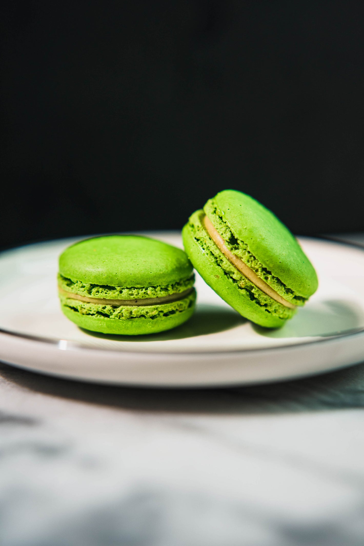 Two green macarons on a plate.