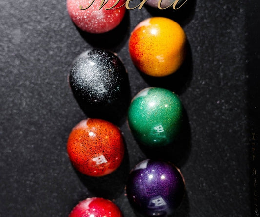 Nine hand-painted bonbons from Hill Country Chocolate arranged on black slate