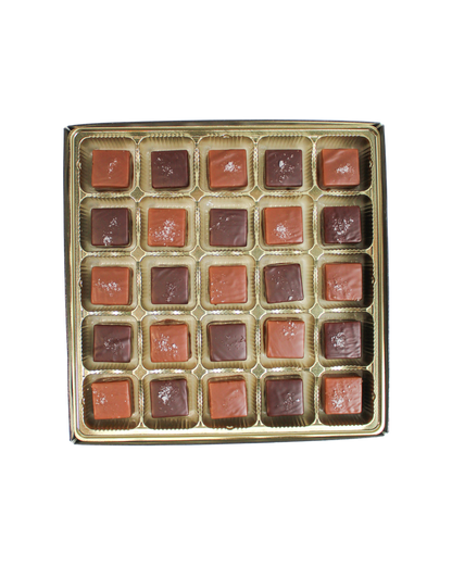 A grid of twenty-five square Hill Country Chocolate Milk & Dark Chocolate Sea Salted Caramels topped with sea salt.
