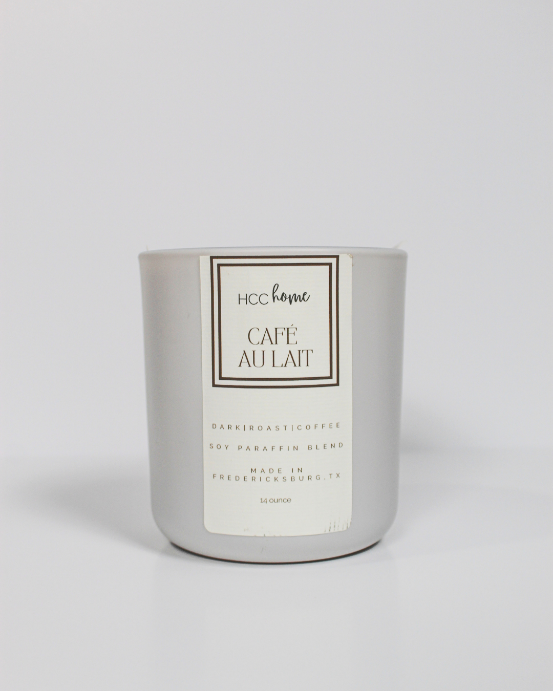 The HCC Home Candle - Cafe Au Lait by Hill Country Chocolate comes in a sleek silver jar and is hand poured in Fredericksburg, TX. This soy-paraffin blend candle captures the essence of rich dark roast coffee and is a genuine Texas-made product.