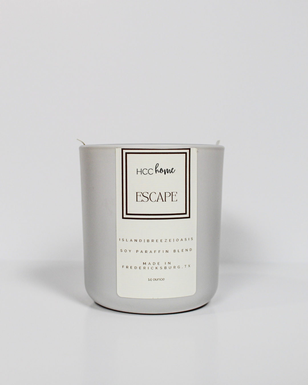 A white HCC Home Candle - Escape by Hill Country Chocolate, presented in a sleek silver container, is displayed against a plain white background—highlighting this hand-poured Fredericksburg, Texas creation as a truly luxurious scented candle designed to elevate your home ambiance.