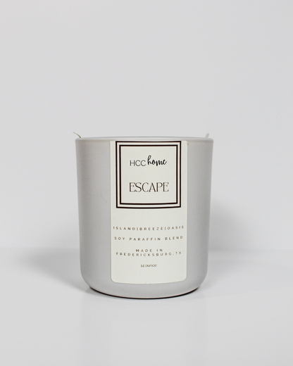 A white HCC Home Candle - Escape by Hill Country Chocolate, presented in a sleek silver container, is displayed against a plain white background—highlighting this hand-poured Fredericksburg, Texas creation as a truly luxurious scented candle designed to elevate your home ambiance.