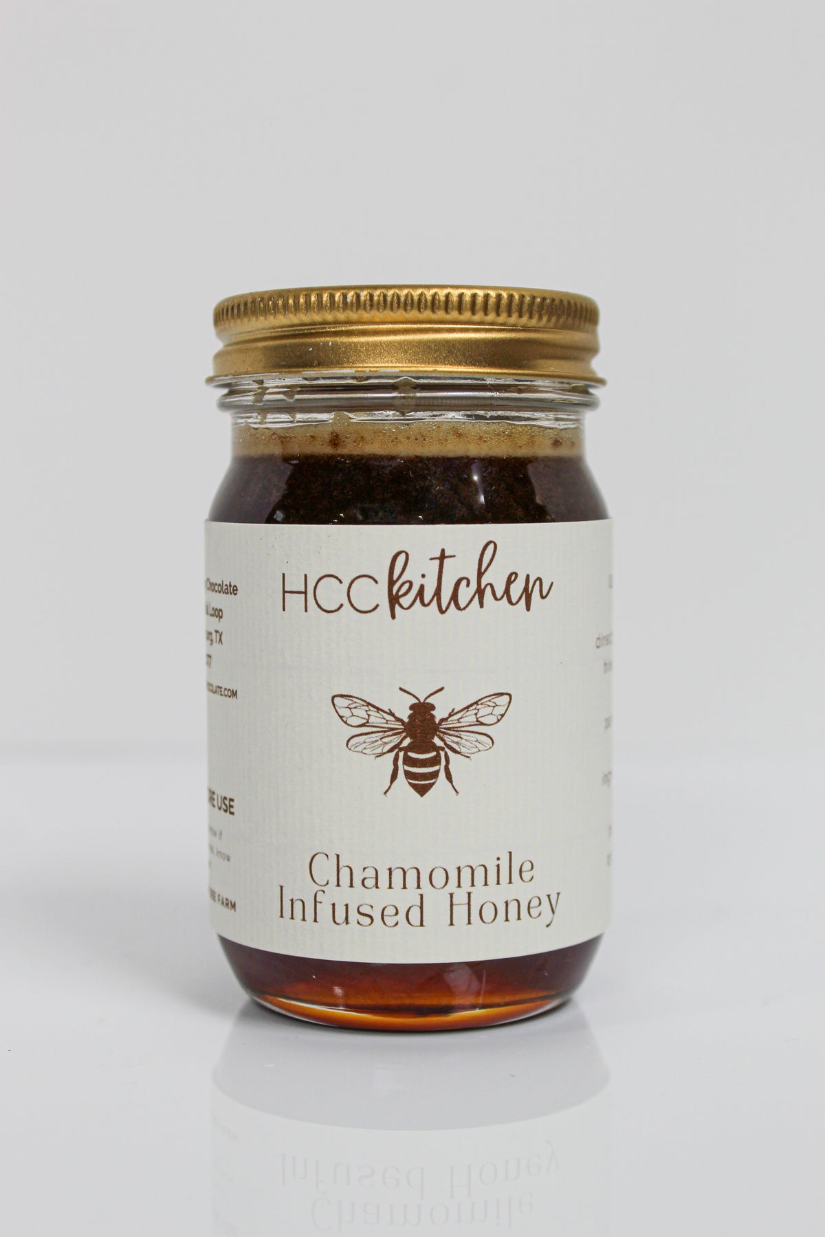 Jar of Hill Country Chocolate Chamomile Infused Honey with a gold lid, showcasing a bee illustration on the label against a plain white background. This soothing honey blends the delicate essence of chamomile with rich natural sweetness.