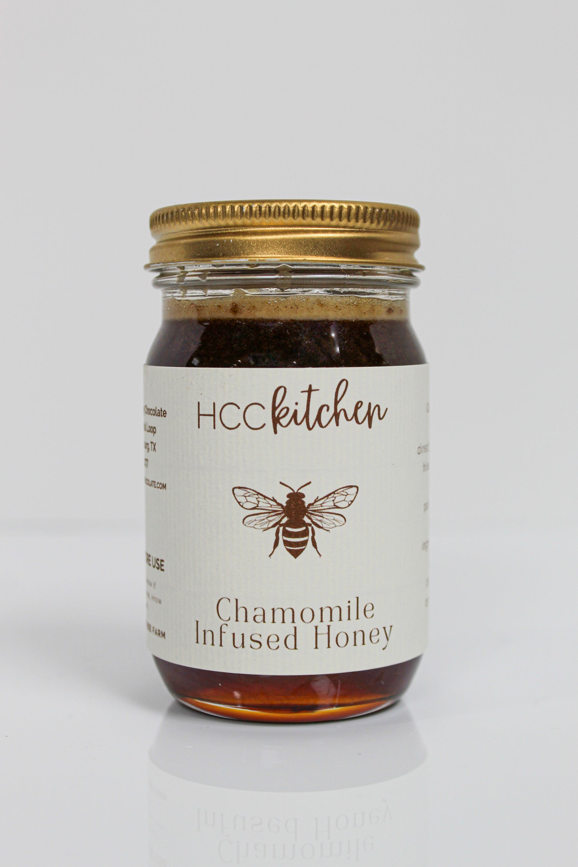 Jar of Hill Country Chocolate Chamomile Infused Honey with a gold lid, showcasing a bee illustration on the label against a plain white background. This soothing honey blends the delicate essence of chamomile with rich natural sweetness.
