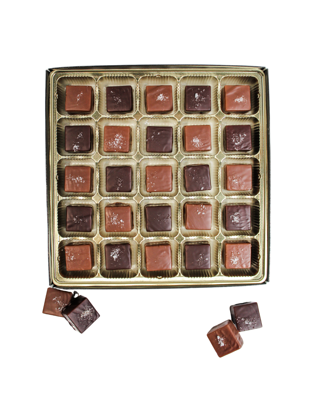 A box of Hill Country Chocolate Milk & Dark Chocolate Sea Salted Caramels, square-shaped and topped with sea salt, with a few extra pieces resting beside the tray.