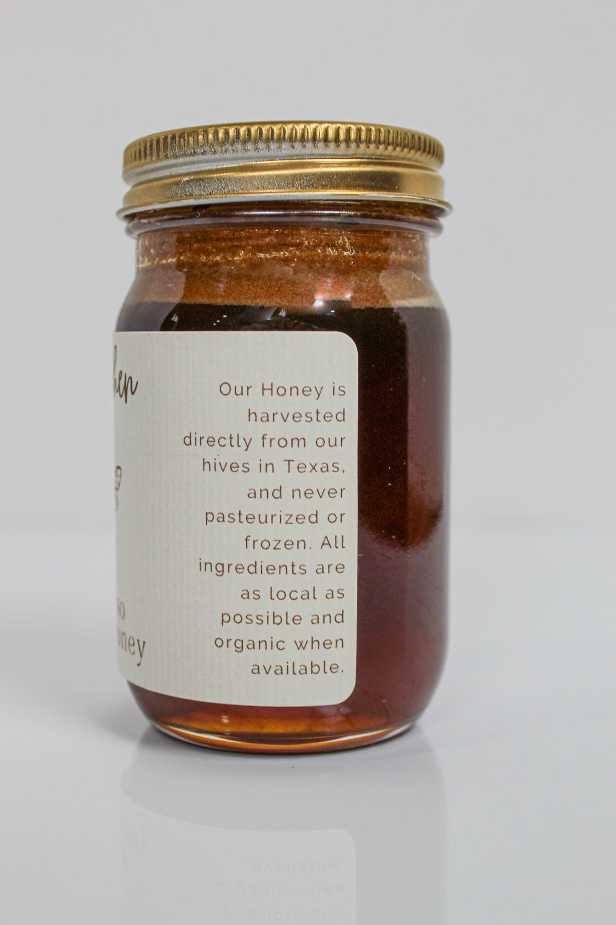 A glass jar of Hill Country Chocolate Lavender Infused Honey with a gold lid and a label stating the honey is raw, harvested in Texas, and made with local, organic ingredients when available.