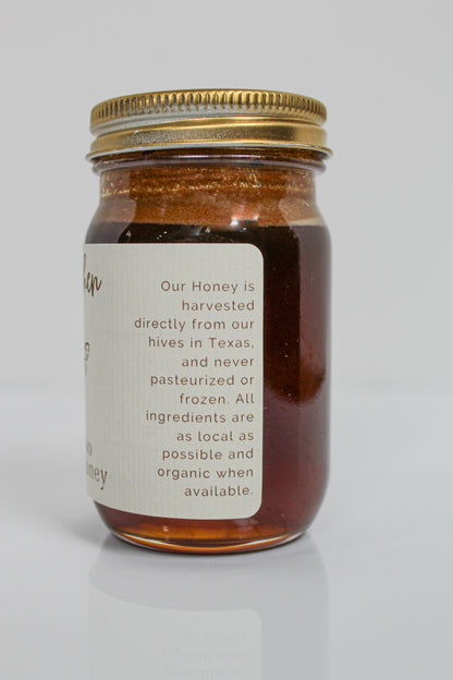 A glass jar of Hill Country Chocolate Lavender Infused Honey with a gold lid and a label stating the honey is raw, harvested in Texas, and made with local, organic ingredients when available.