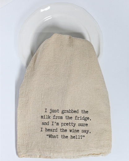 A white plate is partially covered by the Hill Country Chocolate “I just grabbed the milk from the fridge...” tea towel—a funny, eco-friendly cotton kitchen towel that’s perfect for anyone who enjoys a good laugh in the kitchen.