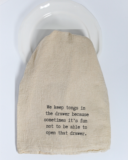A cloth tea towel from Hill Country Chocolate, printed with the text: “We keep tongs in the drawer because sometimes it’s fun not to be able to open that drawer,” adds a playful touch to your natural kitchen. Made from unbleached cotton, this “We keep tongs in the drawer...” Tea Towel brings humor and charm to your home.