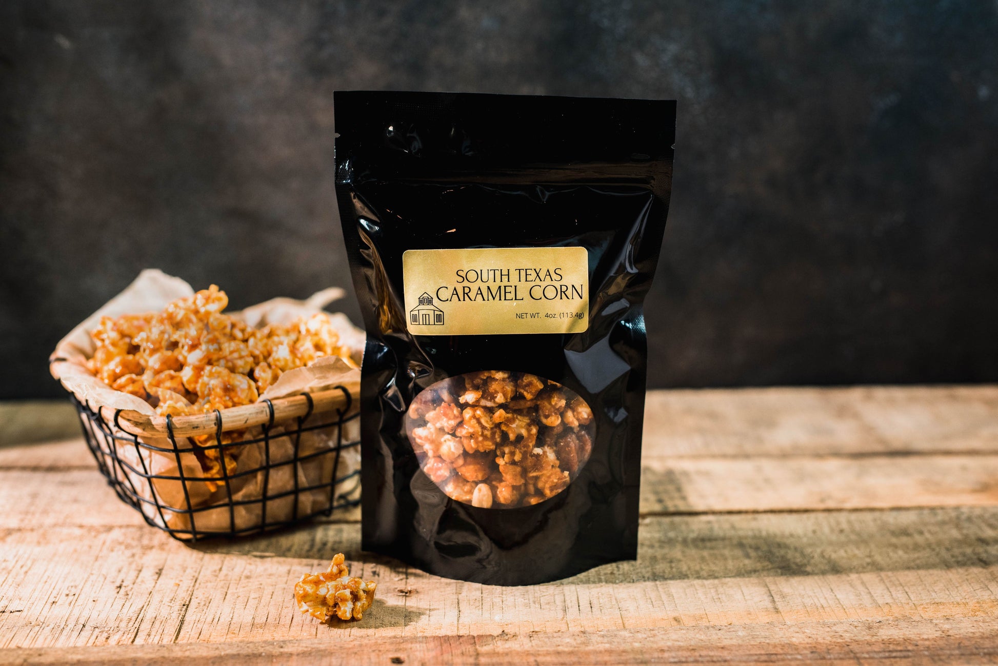 A bag of Spicy South Texas Caramel Popcorn by Hill Country Chocolate sitting on a wooden table at a chocolateshop.